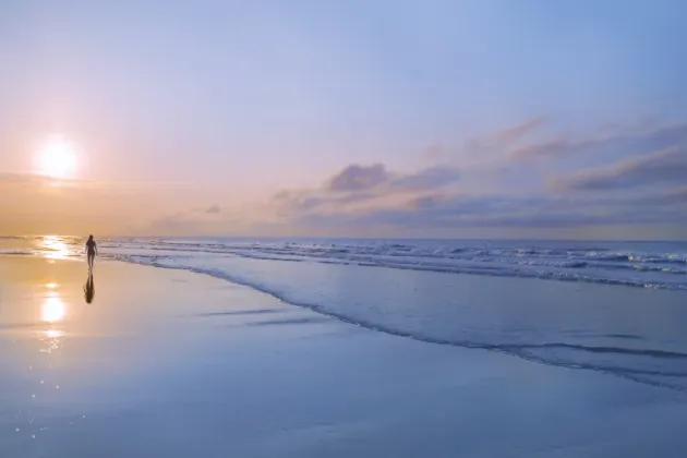 Person går på strand i solnedgång